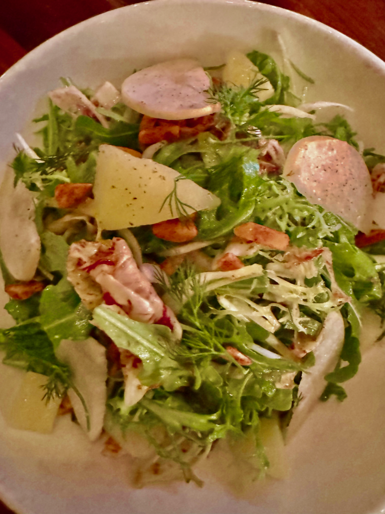 Pear and arugula salad at Byblos featuring peppery greens tossed with thin slices of pear, shaved cheese, fresh herbs, and tender seafood pieces in a light vinaigrette. The fresh vibrant flavors and elegant presentation make it a refined starter for valentine’s day in Canada.