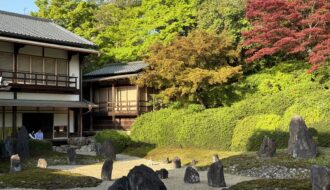 Temple showing rock garden and temple in the background surrounded by trees.