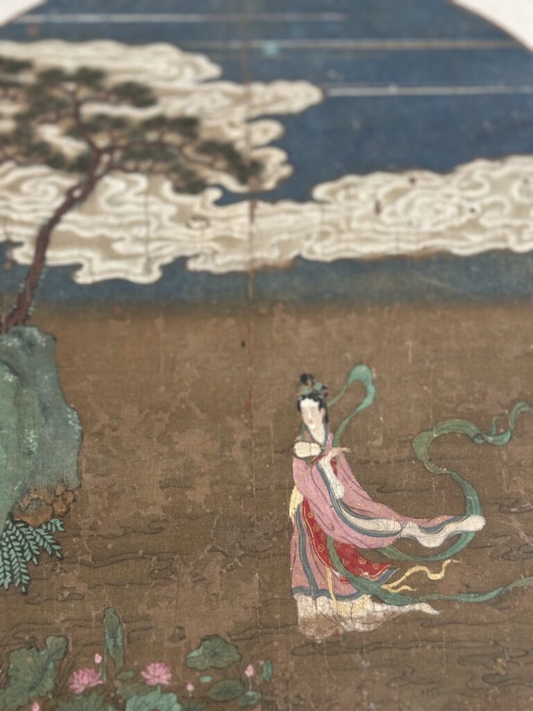 Painting showing a woman in a pink robe with colourful sashes against a mountain and tree backdrop. Part of the antique collection at the Museum of Art and a perfect stop on your 5 day itinerary hong kong.