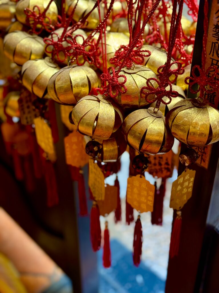 Temple bells in gold with red sashes hanging by a window sill at the famous Man Mo temple. A nice stop on your 5 day hong kong itinerary.