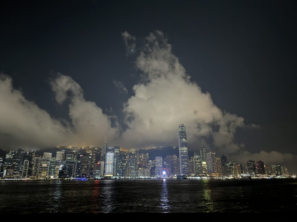 Hong Kong’s skyline glows at night with towering skyscrapers lit against dramatic clouds, while the illuminated Observation Wheel adds a pop of color by the harbor. This vibrant night view captures the city’s energy and is a must-see for any Hong Kong travel itinerary in 3 days.