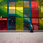 Woman walking across the street with colourful windows in the background in montreal, canada