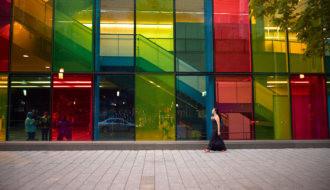 Woman walking across the street with colourful windows in the background in montreal, canada