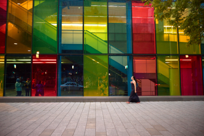 Woman walking across the street with colourful windows in the background in montreal, canada