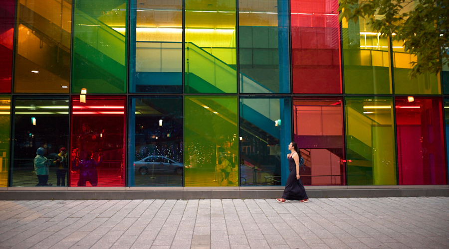 Woman walking across the street with colourful windows in the background in montreal, canada