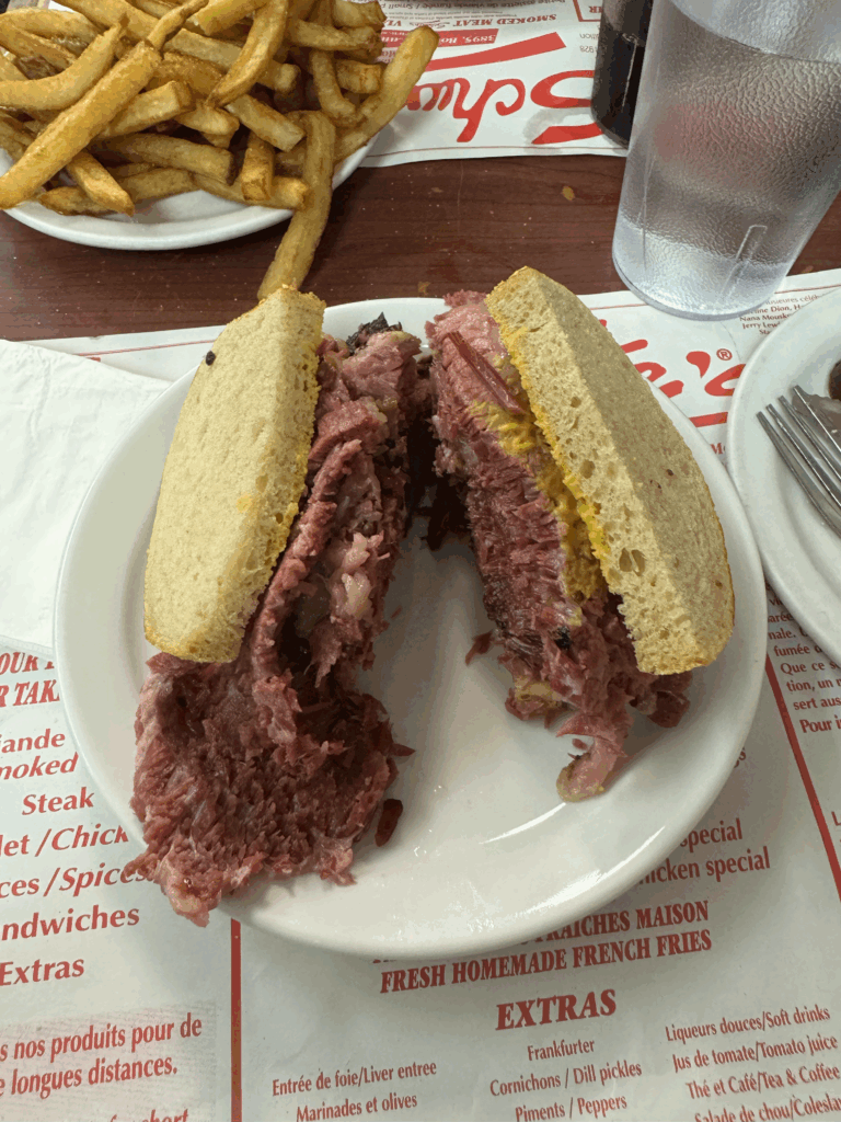 White plate featuring a smoked meat sandwich at Schwartz's. The best place to eat smoked meat in montreal. 