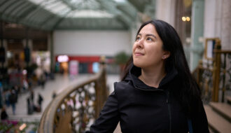 woman wearing black coat inside the train station in paris, france. She is thinking how to pack a carry on for 3 weeks in europe.