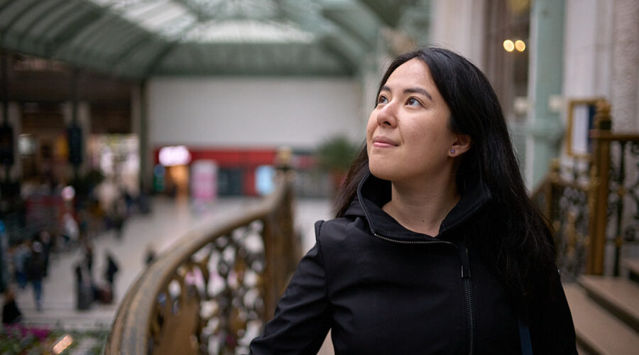 woman wearing black coat inside the train station in paris, france. She is thinking how to pack a carry on for 3 weeks in europe.