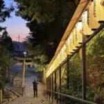 Stone steps descend toward a torii gate at Hachi Shrine in Kyoto as rows of glowing paper lanterns illuminate the path at dusk. The peaceful shrine setting showcases a lesser known stop that can be included in a Kyoto 1 day itinerary for travelers exploring the city’s historic neighborhoods after sunset.