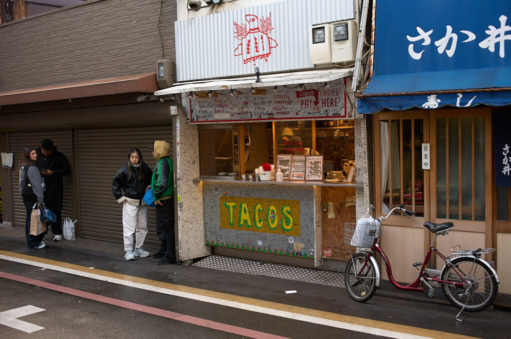 Small taco stand tucked along a narrow Kyoto street with customers gathered outside and a bicycle parked beside the storefront. Discovering casual local eateries and unexpected international food spots adds variety to a Kyoto 1 day itinerary while exploring the city’s neighborhoods beyond the major attractions.
