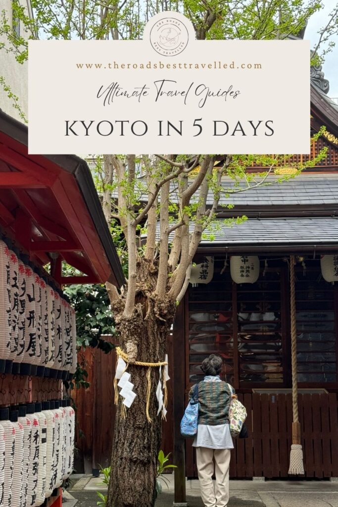 Traditional Kyoto shrine courtyard with rows of paper lanterns, a sacred tree wrapped with shimenawa rope, and a visitor standing in prayer before the shrine. Text on the image reads “www.theroadsbesttravelled.com” “Ultimate Travel Guides” and “Kyoto in 5 Days” introducing a Kyoto itinerary 5 days guide for travelers exploring the city’s temples, shrines, and cultural landmarks.
